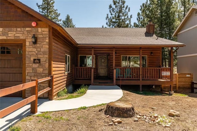 exterior space with faux log siding, a shingled roof, and a porch