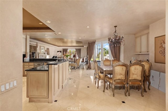 dining space featuring sink, a chandelier, and a raised ceiling