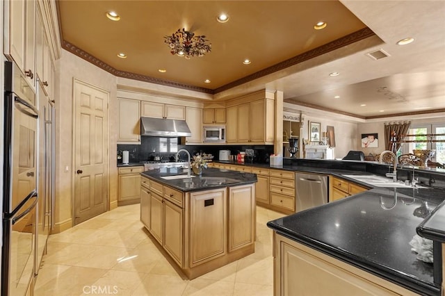 kitchen with a center island with sink, appliances with stainless steel finishes, sink, light brown cabinetry, and kitchen peninsula