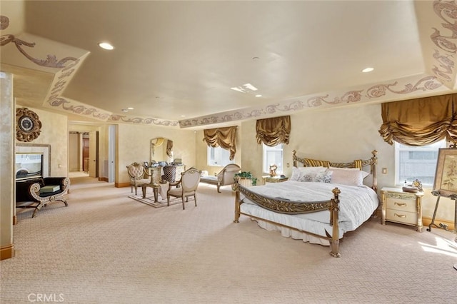 bedroom featuring a tray ceiling, carpet flooring, and a fireplace