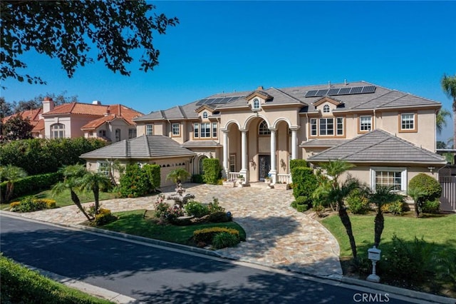 view of front of house with a garage, solar panels, and a front lawn