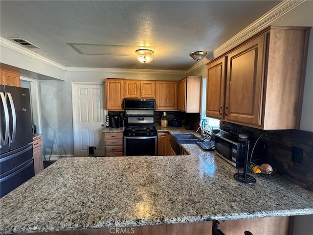 kitchen featuring a peninsula, light stone counters, gas stove, and freestanding refrigerator