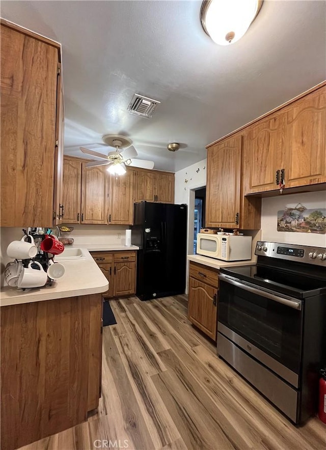 kitchen featuring ceiling fan, stainless steel electric stove, black fridge with ice dispenser, and hardwood / wood-style floors