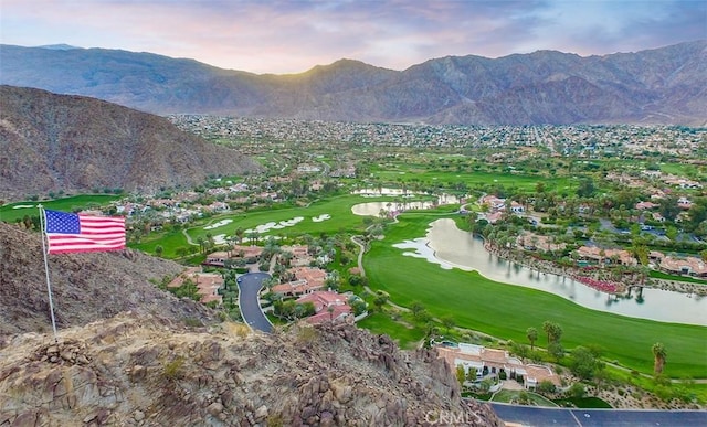 drone / aerial view featuring view of golf course and a water and mountain view