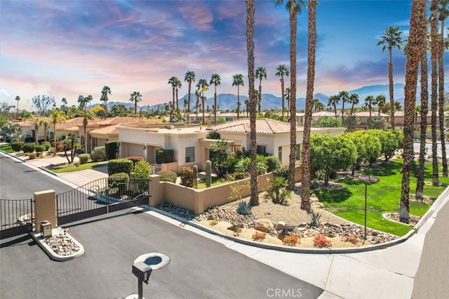 mediterranean / spanish-style home featuring concrete driveway, a gate, fence, a mountain view, and a garage