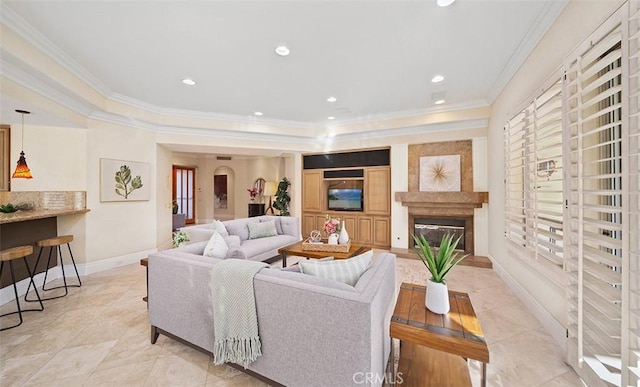 living room with recessed lighting, baseboards, crown molding, and a glass covered fireplace