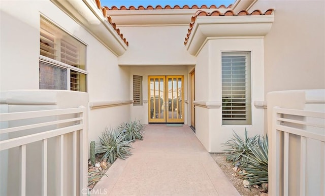 doorway to property with french doors, a tiled roof, and stucco siding