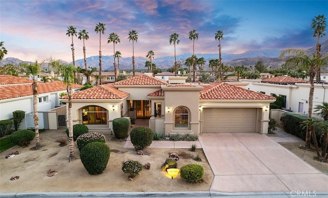 mediterranean / spanish-style house featuring stucco siding, concrete driveway, an attached garage, a mountain view, and a tiled roof