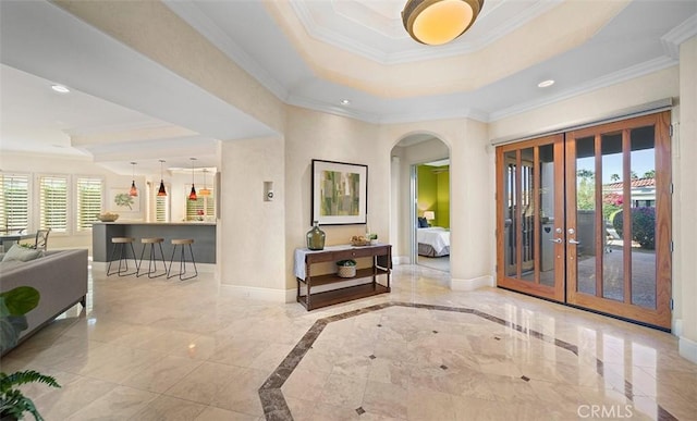 foyer entrance featuring crown molding, a tray ceiling, and baseboards