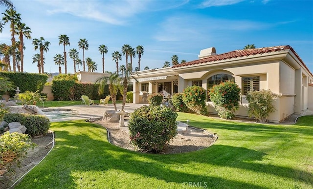 back of property with a tile roof, a chimney, a yard, a patio area, and stucco siding