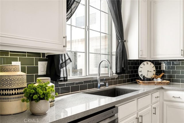 kitchen featuring dishwasher, sink, white cabinets, and light stone counters