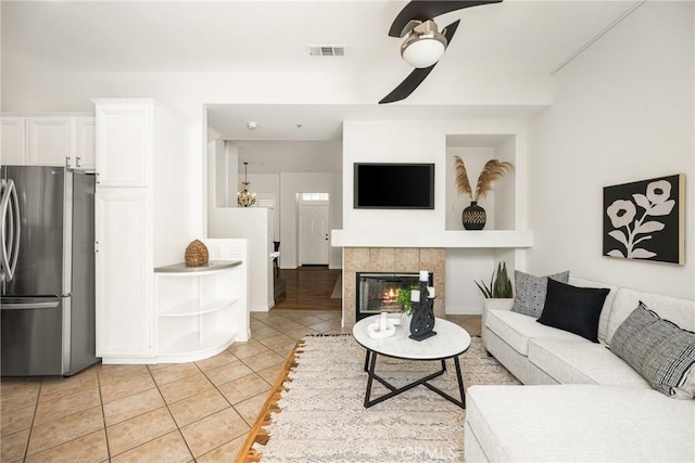 living room featuring light tile patterned flooring, ceiling fan, and a fireplace