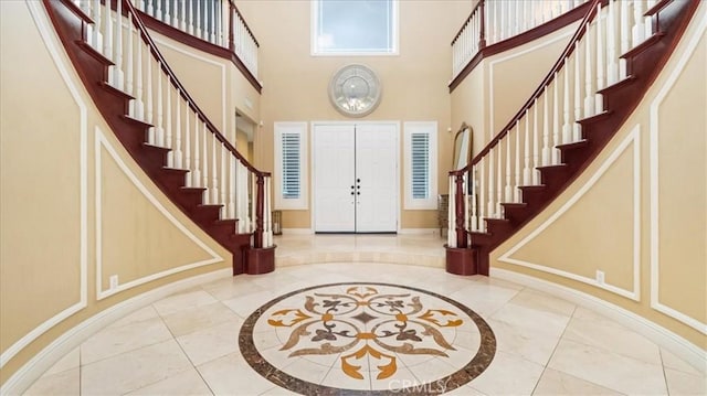 entrance foyer with stairway, a towering ceiling, and baseboards