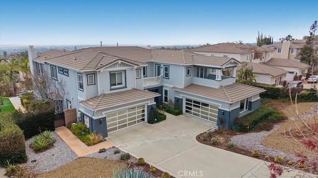 view of front facade featuring a garage, concrete driveway, a tile roof, and a residential view