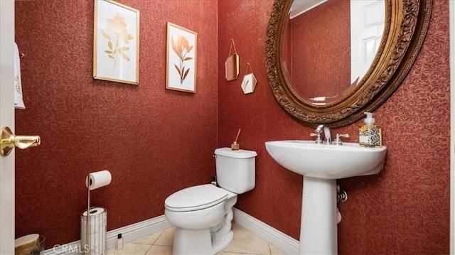 half bathroom with baseboards, toilet, and tile patterned floors