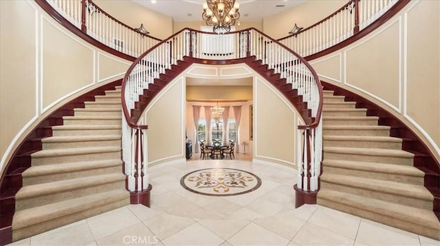 foyer entrance with a chandelier, tile patterned flooring, a towering ceiling, and a decorative wall