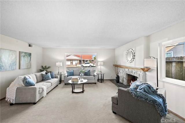 living area featuring light carpet, a fireplace, visible vents, and a textured ceiling