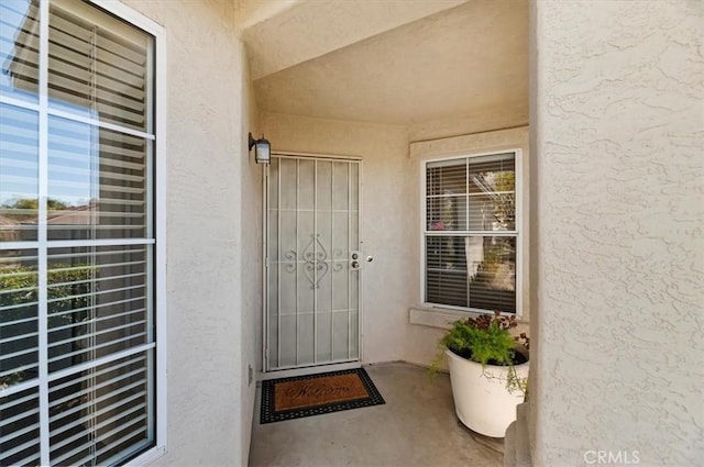 entrance to property featuring a balcony and stucco siding