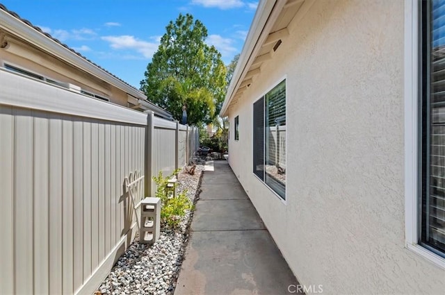 view of side of home with fence and stucco siding