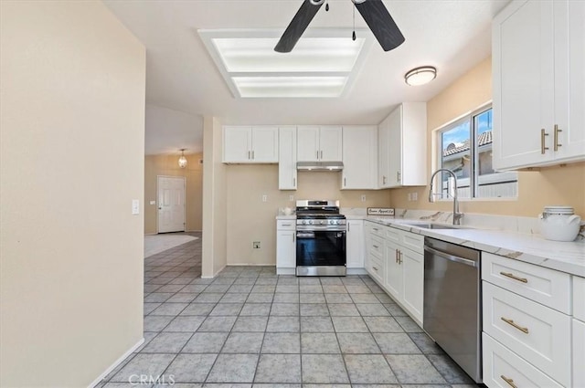 kitchen with light stone counters, appliances with stainless steel finishes, white cabinets, a sink, and under cabinet range hood