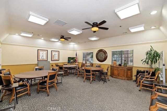 carpeted dining space with ceiling fan, visible vents, and vaulted ceiling