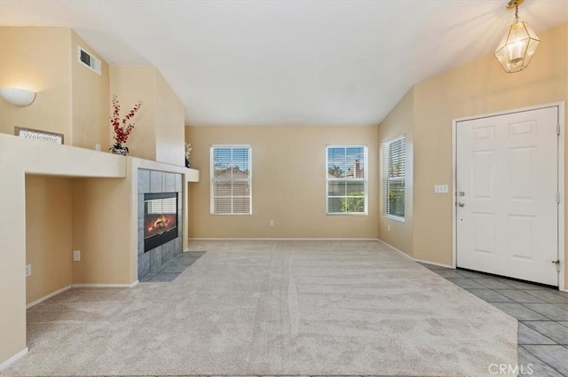 unfurnished living room featuring a healthy amount of sunlight, a fireplace, and light carpet