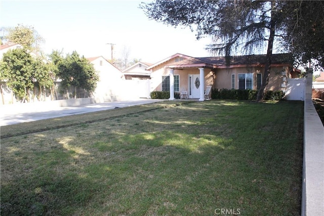 view of front of house with stucco siding, fence, and a front yard