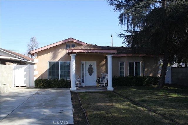 bungalow-style house featuring a front yard, fence, and stucco siding