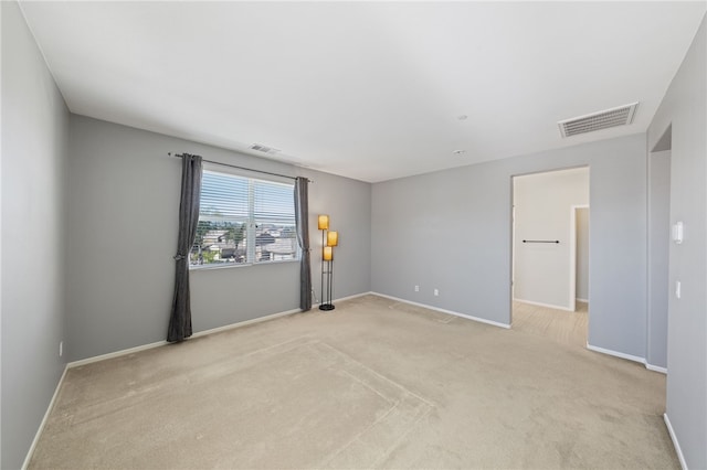 unfurnished room featuring baseboards, visible vents, and light colored carpet