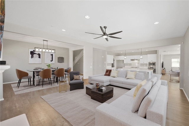 living room with light wood-style floors, recessed lighting, and baseboards