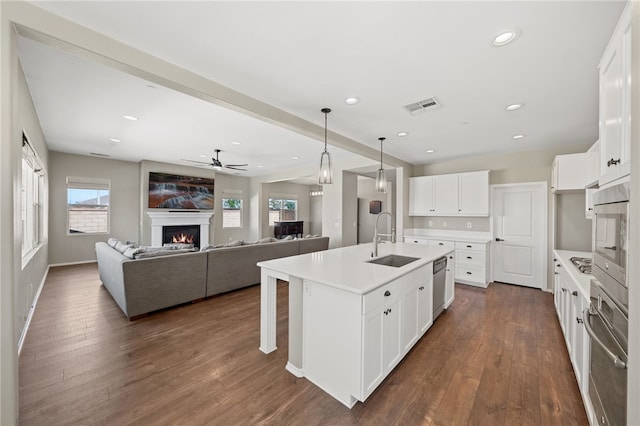 kitchen featuring a kitchen island with sink, a sink, white cabinets, open floor plan, and light countertops