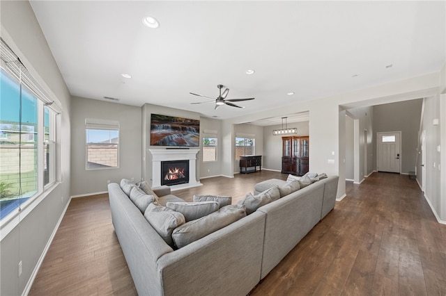 living area with recessed lighting, dark wood-type flooring, visible vents, baseboards, and a glass covered fireplace