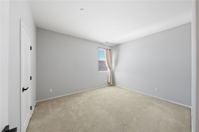 unfurnished room featuring baseboards and light colored carpet