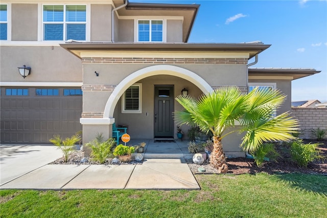 entrance to property with a garage, driveway, and stucco siding