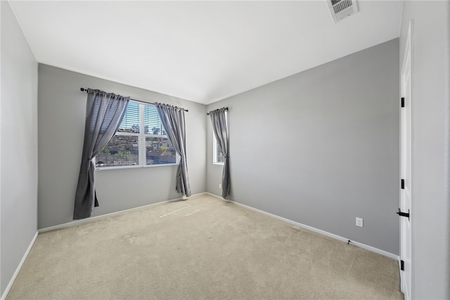 spare room with light carpet, visible vents, and baseboards