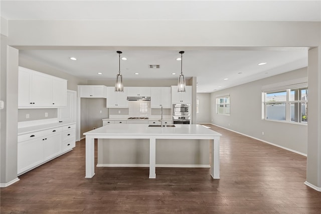 kitchen featuring light countertops, a kitchen island with sink, and white cabinets