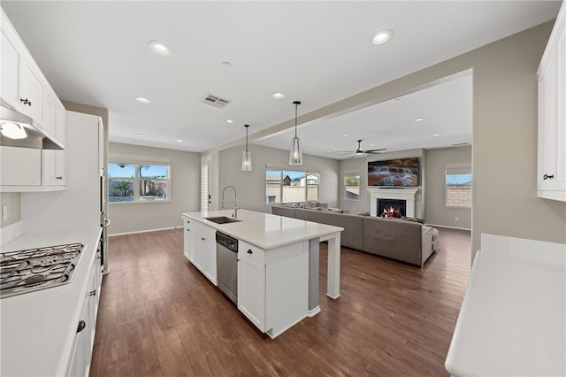 kitchen with open floor plan, light countertops, a center island with sink, and white cabinets