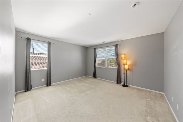 empty room featuring light carpet and baseboards