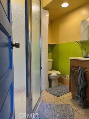 full bath with vanity, tile patterned floors, toilet, and a shower stall