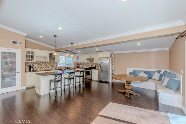 kitchen with dark wood-style floors, a breakfast bar, breakfast area, appliances with stainless steel finishes, and glass insert cabinets