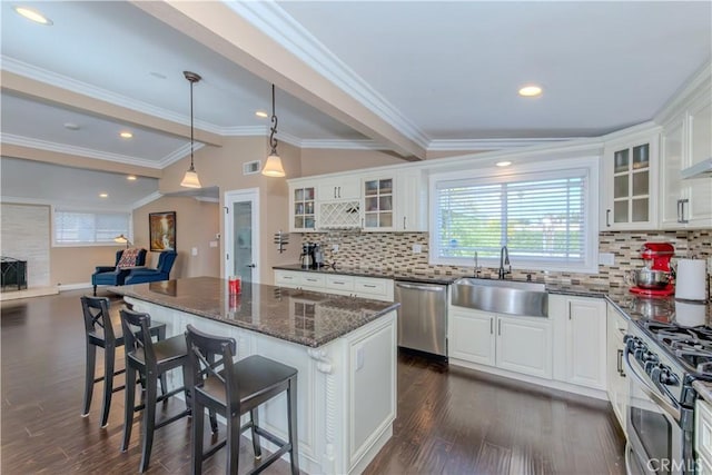 kitchen featuring vaulted ceiling with beams, stainless steel appliances, dark wood-type flooring, a sink, and a center island