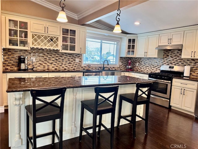 kitchen featuring crown molding, dark wood finished floors, tasteful backsplash, a sink, and gas range