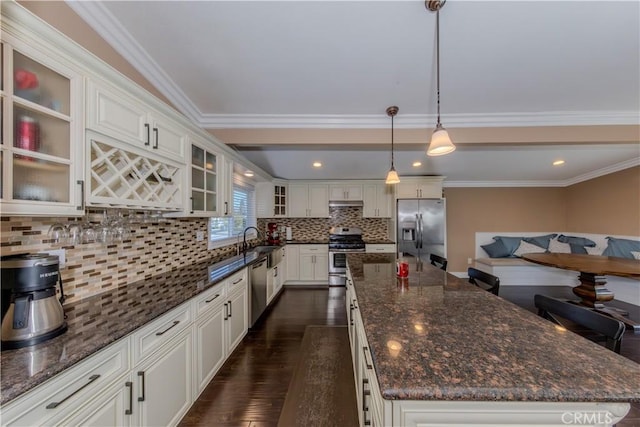 kitchen with dark wood-style floors, a kitchen island, appliances with stainless steel finishes, a sink, and backsplash