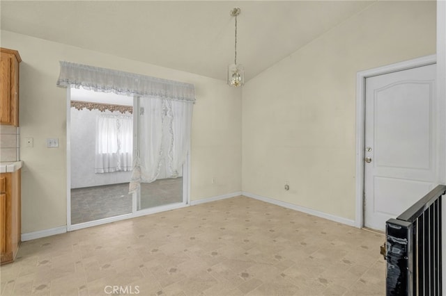 unfurnished dining area featuring light floors, baseboards, and vaulted ceiling