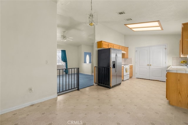 kitchen with stainless steel fridge with ice dispenser, lofted ceiling, white stove, decorative backsplash, and light floors