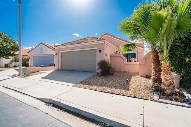 mediterranean / spanish-style home with a garage, driveway, a tile roof, and stucco siding