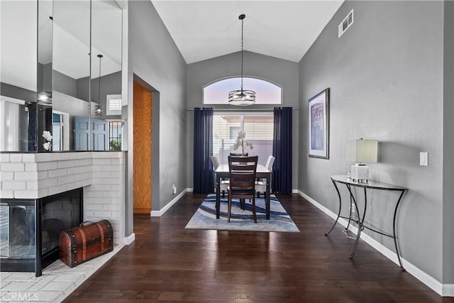 dining space featuring a fireplace, visible vents, wood finished floors, high vaulted ceiling, and baseboards