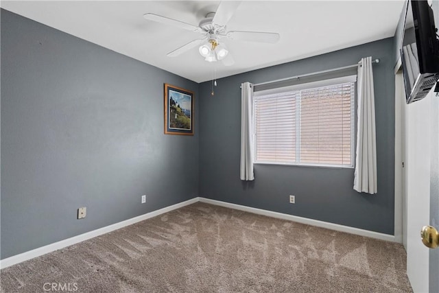 carpeted empty room featuring ceiling fan and baseboards