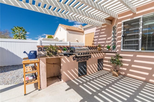 view of patio featuring area for grilling, an outdoor kitchen, fence, and a pergola