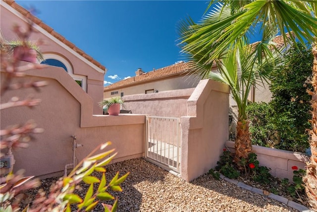 exterior space with a gate, fence, and stucco siding